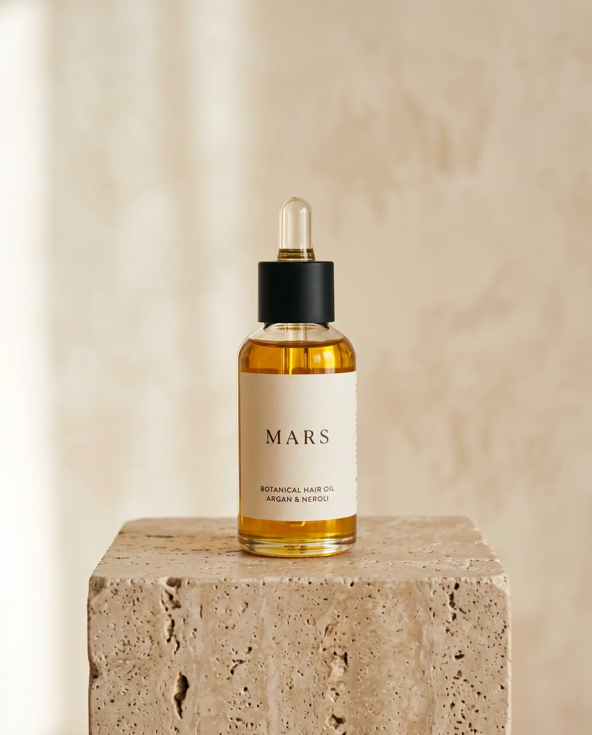 Bottle of Botanical Hair Oil with argan and neroli on a travertine plinth against cream limewash
